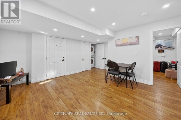 Basement living area with wood floors, recessed lighting, and doors leading to laundry and another room. - 2 - 33 Andretti Crescent, Brampton