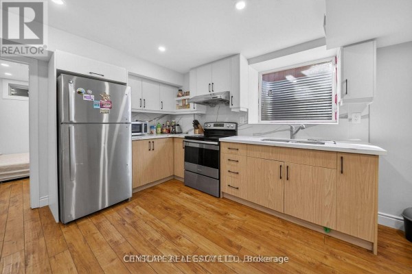 Corner kitchen with light wood cabinets, stainless steel appliances, and a window above the sink. - 2 - 33 Andretti Crescent, Brampton