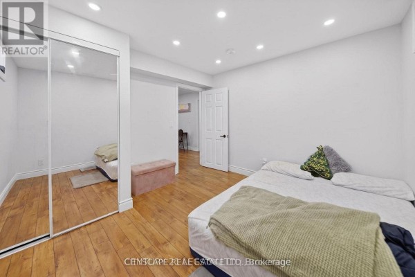 Bedroom with wood floors, a large mirrored closet, and a bed with green and brown bedding. - 2 - 33 Andretti Crescent, Brampton