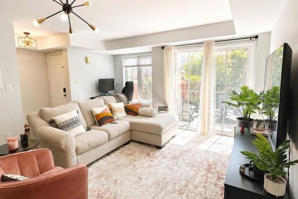 Living room with a beige sectional sofa, pink accent chair, and large windows. - 2 - 35 Hays Boulevard, Oakville