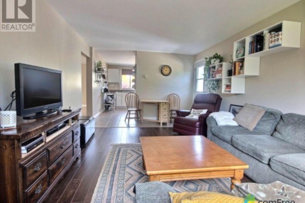 Living room with television, dresser, sofa, recliner, coffee table, and view into kitchen. - 2 - 3784 Sinnicks Avenue, Niagara Falls