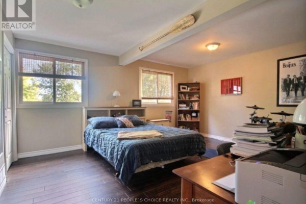 Bedroom with queen bed, desk, chair, window, and wooden floors. - 2 - 3784 Sinnicks Avenue, Niagara Falls
