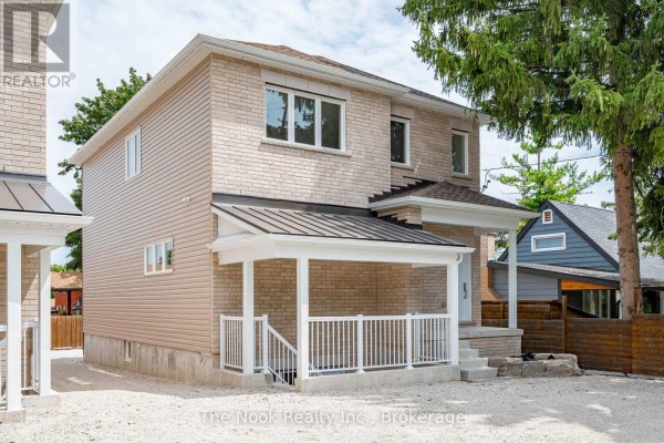 Side and front exterior view of a beige brick multi-family home with a covered porch and white railing. - 1 - 399 Thorton Road N, Oshawa