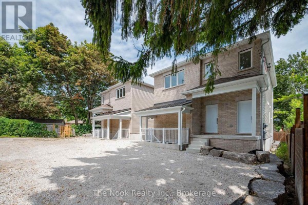 View of the side and front of two beige brick multi-family homes with covered porches, surrounded by trees. - 1 - 399 Thorton Road N, Oshawa