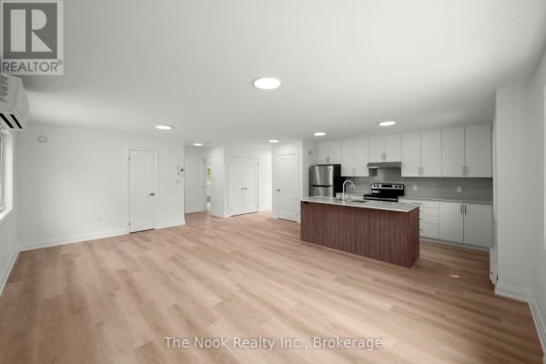 View of the open-concept living space, kitchen island, and white cabinetry. - 2 - 403 Thornton Road N, Oshawa