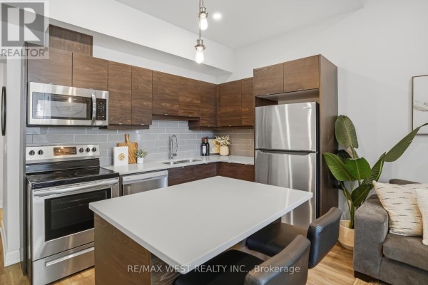 Kitchen with dark wood cabinets, stainless steel appliances, and a central island. - 2 - 405 Merritt Street, St  Catharines