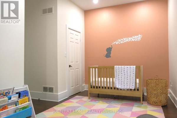 Nursery with salmon pink wall, elephant decal, crib, and colorful rug. - 2 - 41 Spruce Street, Toronto