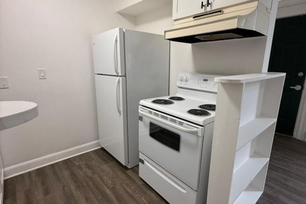 A compact kitchen with white appliances including a refrigerator and a stove, plus white cabinets. - 2 - 42 Toronto Street, Barrie