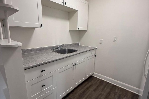 A kitchen with a stainless steel sink, grey countertop, and white cabinets below and above. - 2 - 42 Toronto Street, Barrie