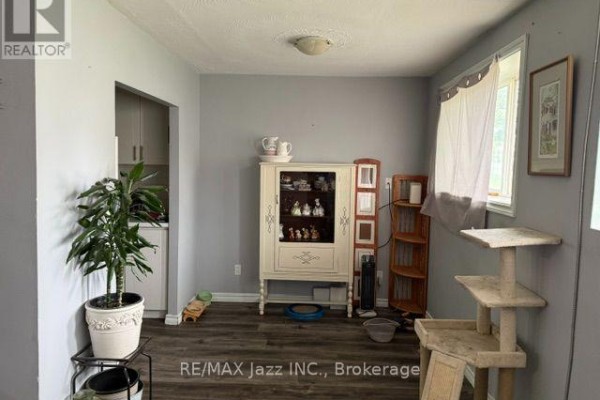 A dining area with dark wood laminate flooring, a china cabinet, and a plant. - 2 - 43 Wayne Avenue, Oshawa