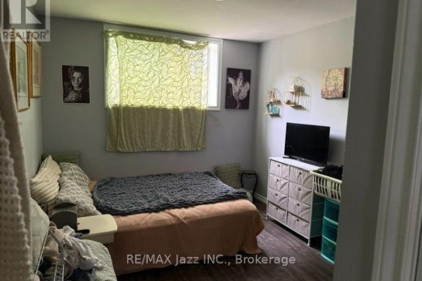 A bedroom with a queen-size bed, a dresser with a television, and a window with patterned curtains. - 2 - 43 Wayne Avenue, Oshawa