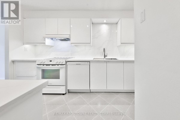 Modern white kitchen with glossy cabinets, white appliances, and a marble backsplash. - 2 - 4635 Regents Terrace, Mississauga
