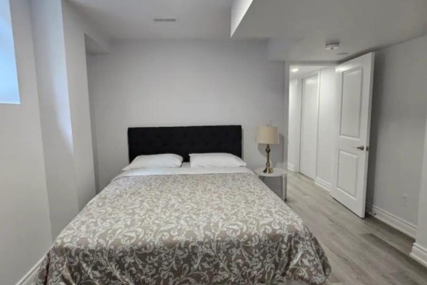 Bedroom with a bed, nightstand, lamp, and doors to hallway and closet. - 2 - 54 Baycliffe Drive, Whitby