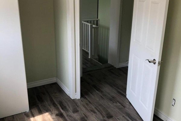 Hallway view showing a staircase leading down, with two doorways and laminate flooring. - 2 - 54 Markham Street, Toronto