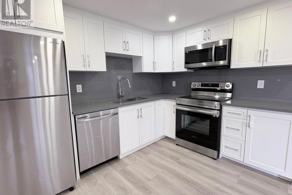 White kitchen cabinets with grey quartz countertops and stainless steel appliances. - 2 - 63 Champlain Avenue, Hamilton