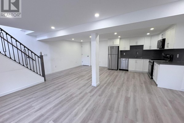 Open concept living area with stairs, kitchen, and white walls. - 2 - 63 Champlain Avenue, Hamilton