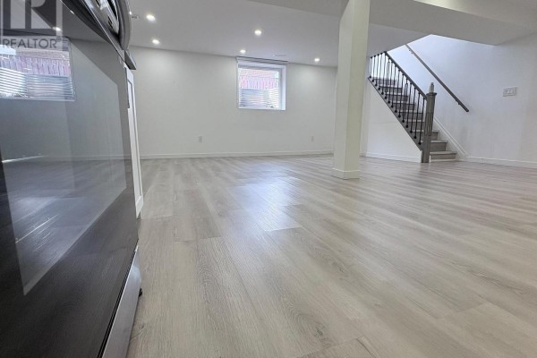 View of staircase, white walls, and wood-look laminate flooring in open space. - 2 - 63 Champlain Avenue, Hamilton