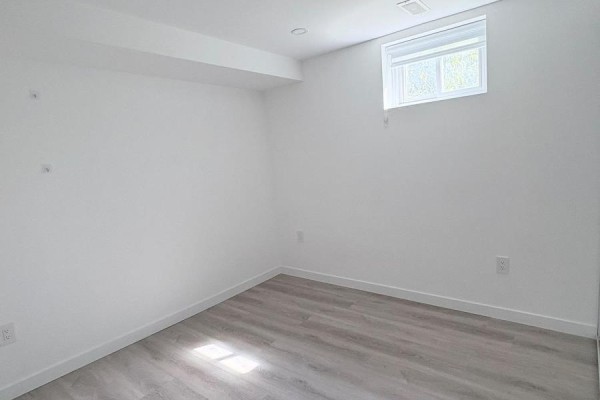 Empty room with white walls, a window, and light wood-look laminate flooring. - 2 - 63 Champlain Avenue, Hamilton
