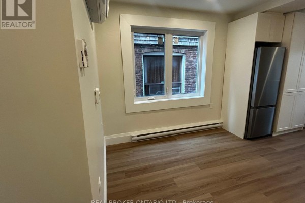 Kitchenette with white cabinets, stainless steel appliances, and window view of brick building. - 2 - 659 Vaughan Road, Toronto
