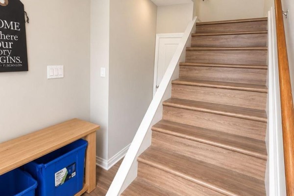 Interior staircase with light brown wood-look laminate flooring and white railing. - 2 - 6610 Fourth Line Road, Ottawa