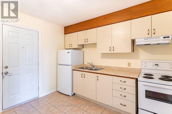 Kitchen with cream-colored cabinets, a beige countertop, white appliances, and tiled flooring. - 2 - 718 Ross Street, Burlington