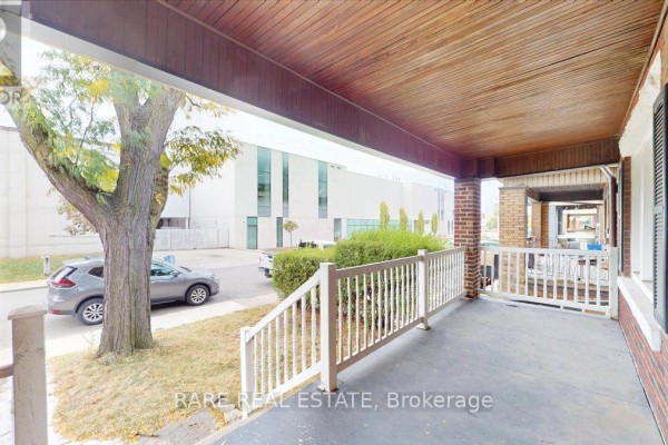 View from the covered porch showing a tree, parked car, and adjacent buildings. - 2 - 8 Balsam Avenue N, Hamilton