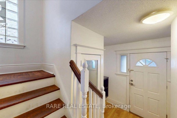 Interior view of a hallway with wooden stairs, white banister, and white front door. - 2 - 8 Balsam Avenue N, Hamilton