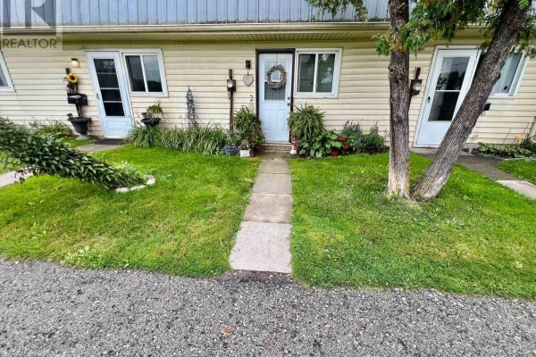 Close-up of the front entrance of a cream-colored townhouse with a white door and a stone walkway. - 2 - 8646 Willoughby Drive, Niagara Falls