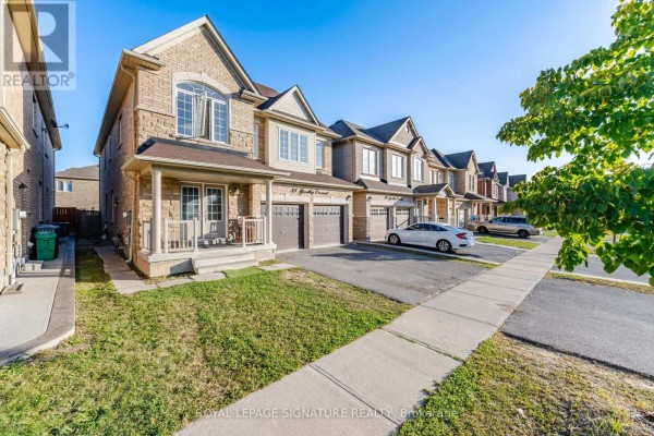 Side view of a row of townhouses with driveways, lawns, and sidewalks under a clear sky. - 2 - 88 Yardley Crescent, Brampton