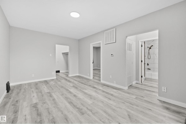Living area with light gray walls, light wood-look flooring, and doorways to a closet and bathroom. - #2 10049 154 St Nw, Edmonton
