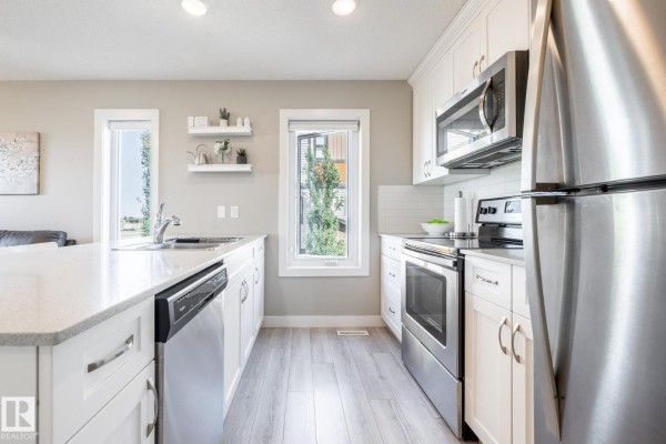 Close-up of kitchen with stainless steel fridge and stove, white cabinets - #2 1203 163 St Sw, Edmonton