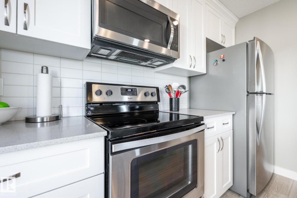 Bright kitchen area with windows, white cabinets, and light wood flooring - #2 1203 163 St Sw, Edmonton