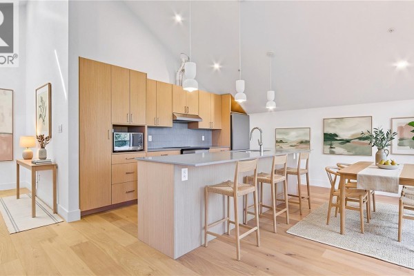 Kitchen with light wood cabinets, island, bar stools, and dining area. - 2 1721 Adanac St, Victoria