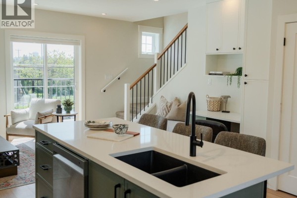 Kitchen island with white counters and a green base, adjacent to stainless steel appliances and white cabinets. - 2 1830 Allenby St, Saanich