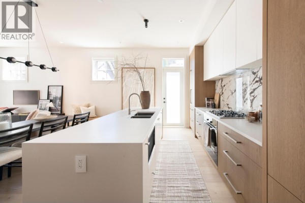 Kitchen island with a sink, facing a long counter with appliances and cabinets. - 2 2119 W 18th Avenue, Vancouver