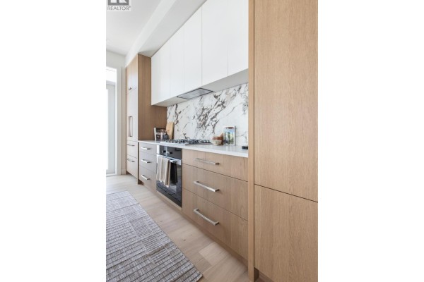 Kitchen counter with a stove and oven, surrounded by white and wood cabinets. - 2 2119 W 18th Avenue, Vancouver