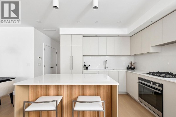 Kitchen island with seating and a fluted wood base, facing contemporary cabinets and stainless steel oven. - 2 2124 E 8 Avenue, Vancouver