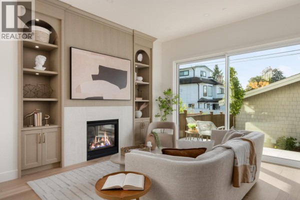 Living room with fireplace, built-in shelves, modern sofa, and large sliding glass door. - 2 2344 W 45th Avenue, Vancouver