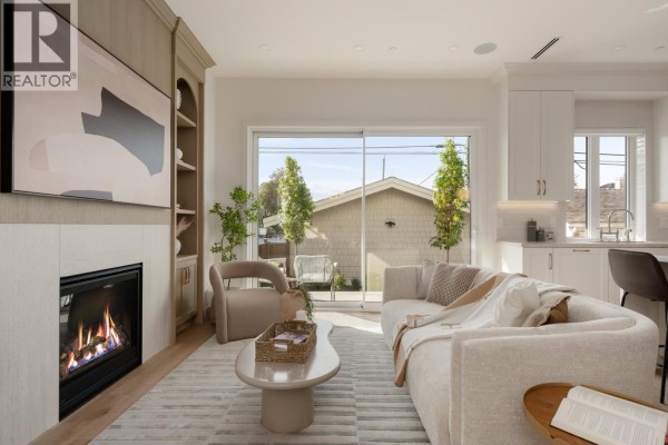 Living room with fireplace, built-in shelves, sofa, coffee table, and sliding glass door to backyard. - 2 2344 W 45th Avenue, Vancouver