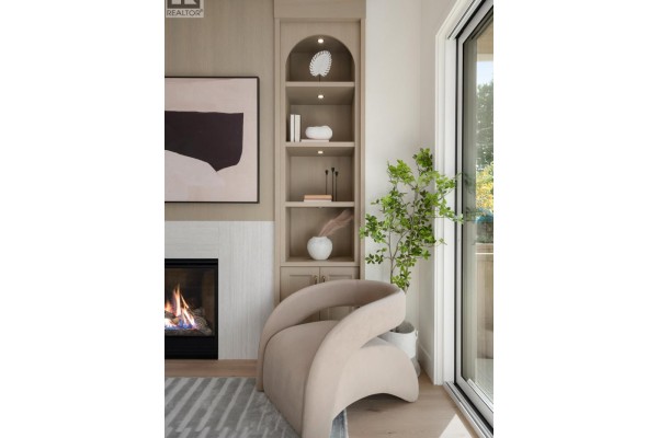 Close-up of a living room fireplace with built-in shelving, a modern chair, and sliding glass door. - 2 2344 W 45th Avenue, Vancouver