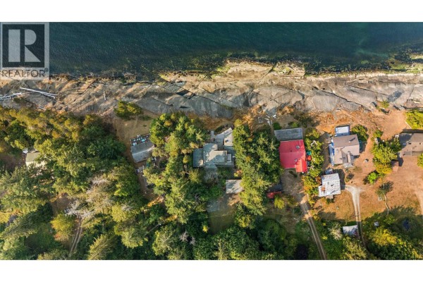Aerial view of waterfront properties with a red-roofed building and dense trees. - 2 37 Salamanca Road, Galiano Island