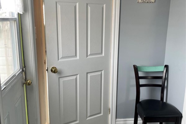 Interior entryway with white doors, gray walls, and a dark chair with a green back. - 2-4 Russell's Lane, Bonavista