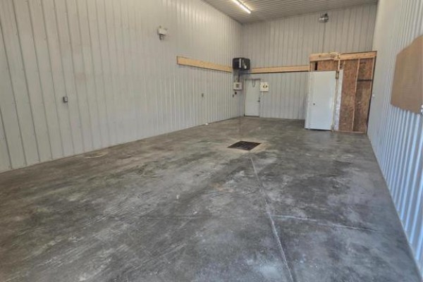 Interior view of an empty warehouse with concrete floor, metal walls, and overhead lighting. - 2 44 Industrial Road, Steinbach