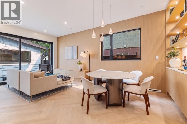 Living and dining area with a sectional sofa, round dining table, and built-in wood shelving. - 2 4956 Chester Street, Vancouver