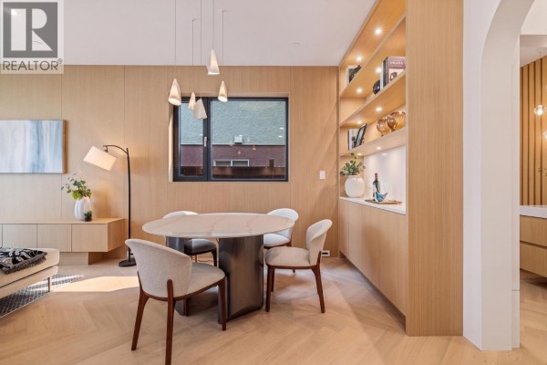 Dining area with a marble-topped table, upholstered chairs, and floor-to-ceiling wood cabinetry with display shelves. - 2 4956 Chester Street, Vancouver