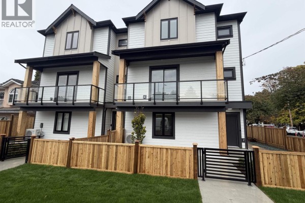 Townhouse exterior with balconies, glass railings, and wood fencing under a cloudy sky. - 2 7497 Holly Street, Burnaby