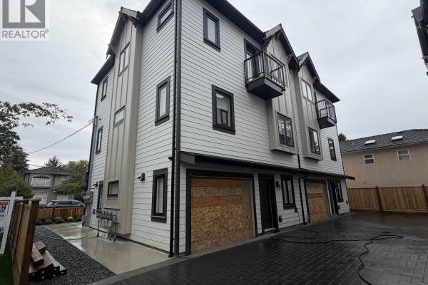 Side view of a townhouse complex showing garage doors boarded with plywood. - 2 7497 Holly Street, Burnaby