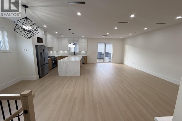 Modern kitchen with white cabinets, stainless steel appliances, and a large waterfall island. - 2 7497 Holly Street, Burnaby