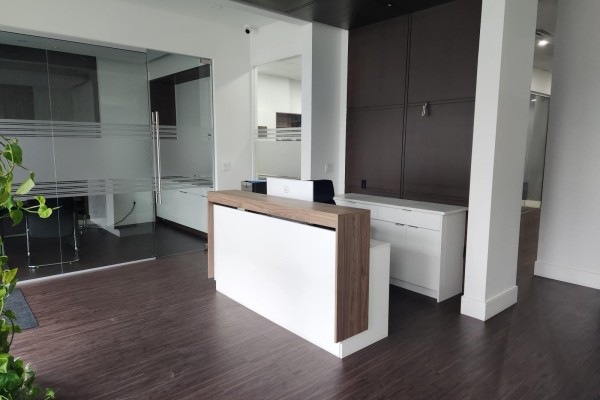 Empty reception area with a white and wood reception desk and glass-walled offices. - 2 9015 120 Street, Delta