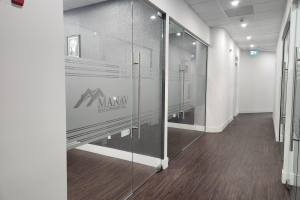Office hallway with glass-walled offices featuring frosted banding and dark wood flooring. - 2 9015 120 Street, Delta